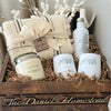 Gift set with candles, tumblers, and a blanket in a wooden crate labeled 'The Daniel Homestead'.