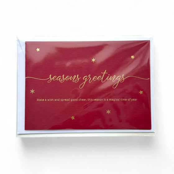 Red greeting card with gold embossed 'seasons greetings' text and stars on a white background
