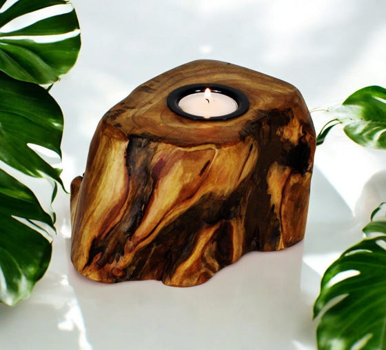 Single Live Edge Root Wood Candle Holder on white surface with palm leaves.