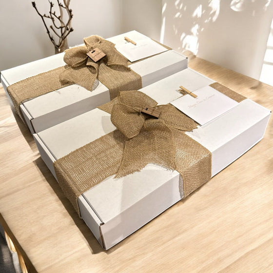 White gift boxes with burlap ribbons on a wooden surface