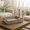 rectangualr rustic woodden tray with cut our side handles on a wood coffee table with books and candles next to it.  