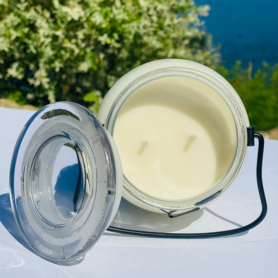 Inside of  a 2 wick glass candle jar with black metal carrying handle and glass lid 